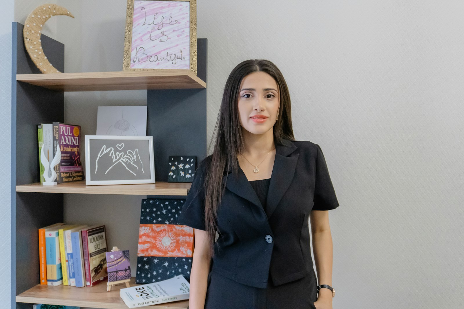 Woman in a black suit standing by a bookshelf