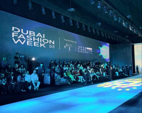 The Dubai Fashion Week runway and seating at Dubai Design District, with the event backdrop lit in blue