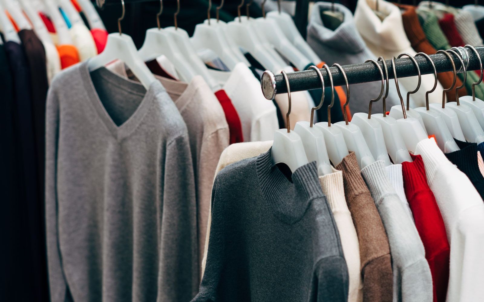Racks of low-cost knitwear on plastic hangers, illustrating the question is Shein legit and fast fashion law