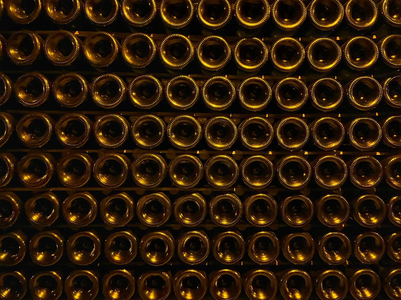 Rows of champagne bottle bases stacked on their sides in a dark cellar, representing LVMH's wine houses
