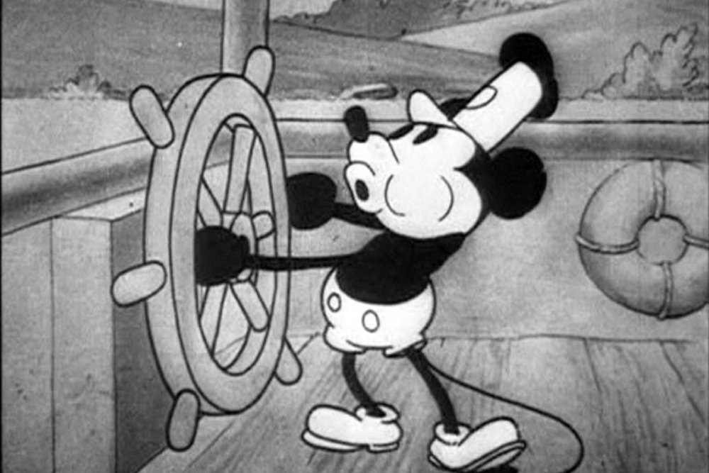 Black and white frame from the 1928 cartoon Steamboat Willie showing Mickey Mouse at a ship's wheel