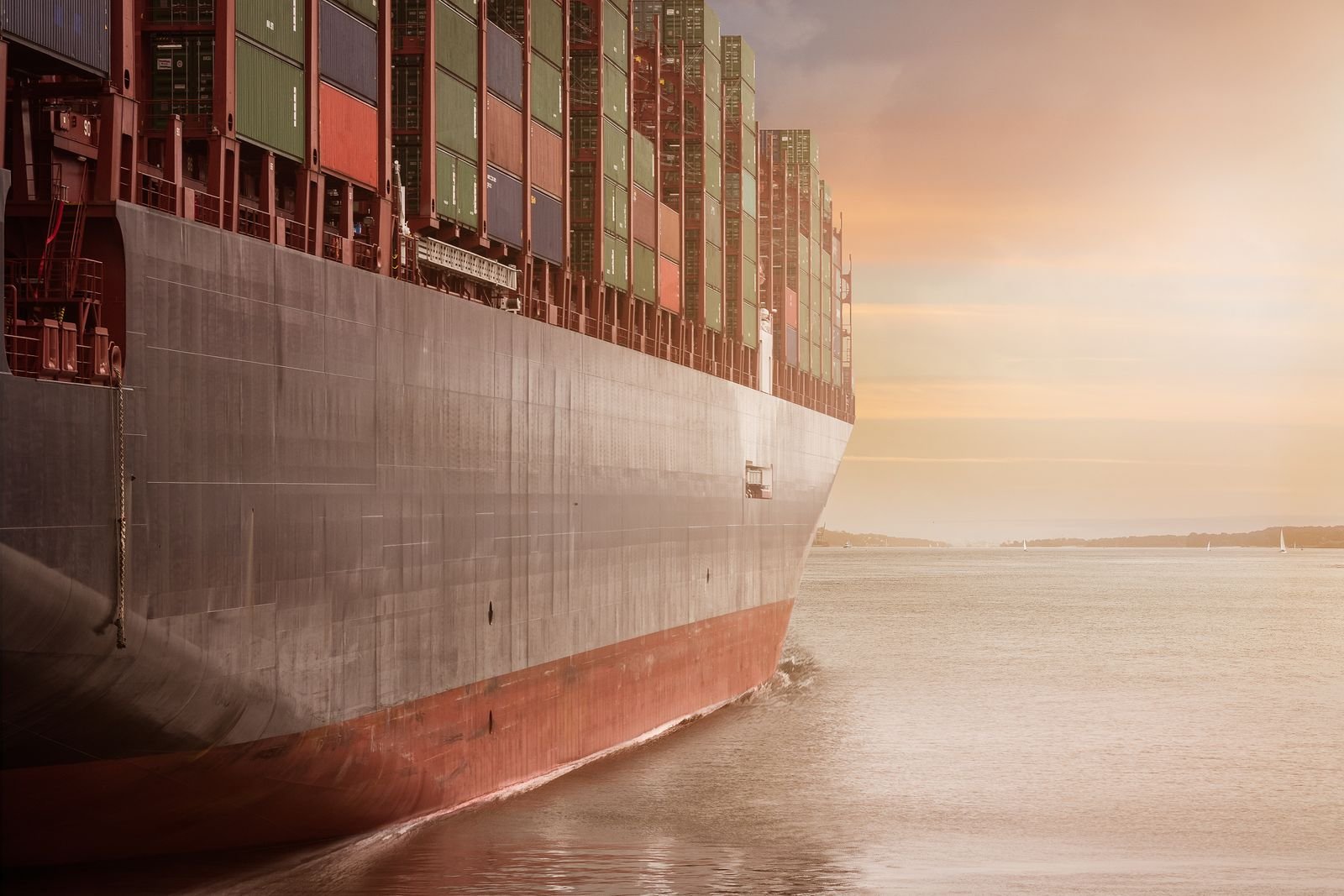 Loaded container ship sailing at sunset, representing PVH's imported apparel and US tariffs