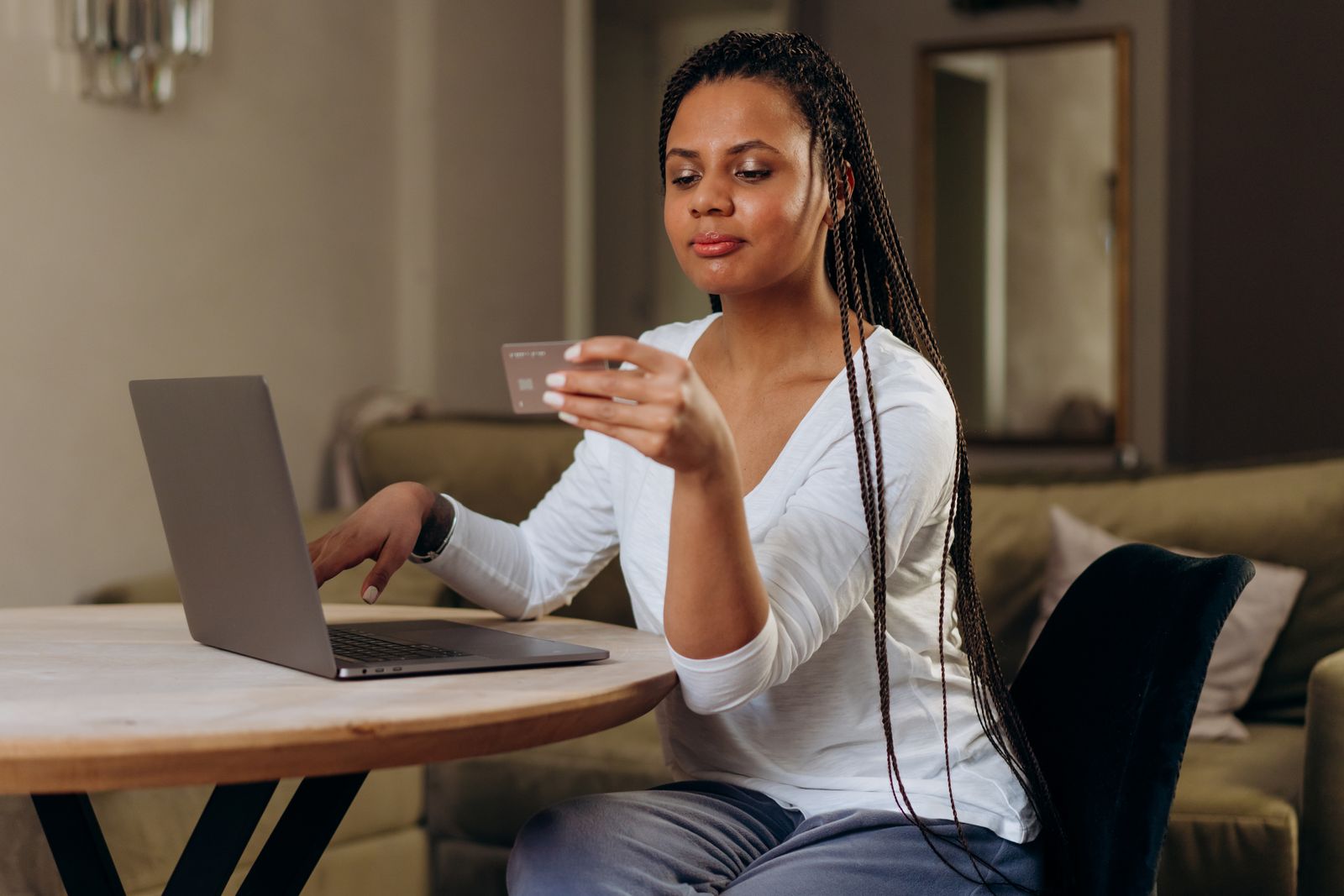 Woman holding a bank card while shopping online on a laptop at home
