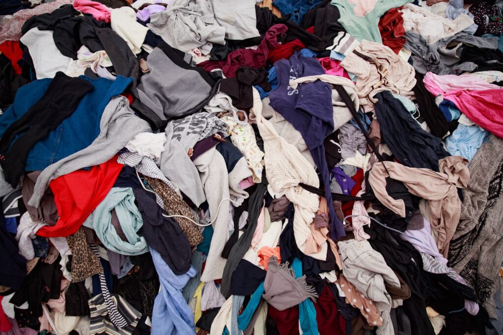 Large pile of discarded mixed clothing in many colours waiting to be sorted for reuse or recycling