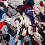 Large pile of discarded mixed clothing in many colours waiting to be sorted for reuse or recycling