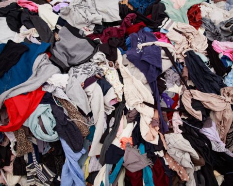 Large pile of discarded mixed clothing in many colours waiting to be sorted for reuse or recycling