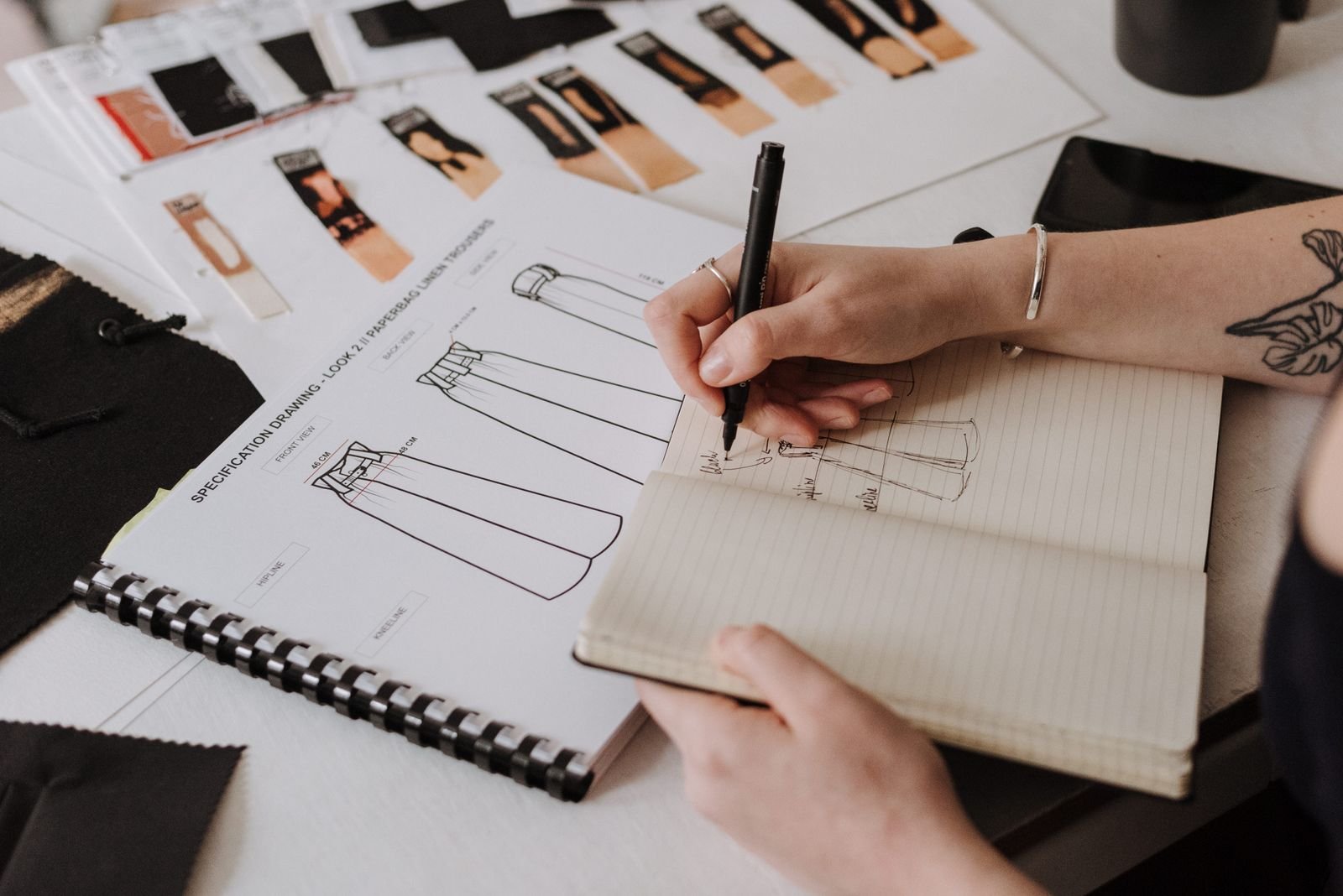 Fashion designer sketching garment designs before running a trademark search on a new brand name